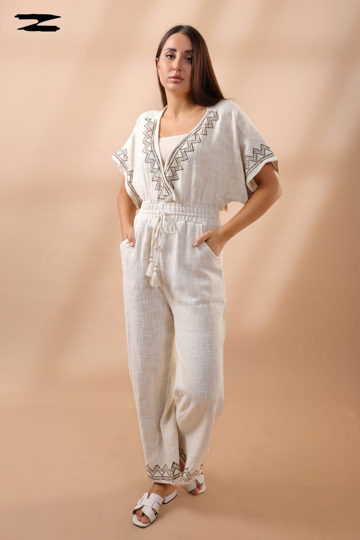 Woman wearing a white outfit with embroidery on a beige background